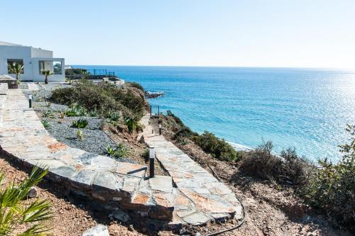 a stone path next to the ocean with a house at Evgoro - Infinite View in Tsoútsouros