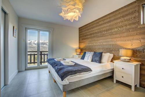 une chambre avec un grand lit avec un mur en bois dans l'établissement Apt. Marmottes -Fabulous 3 bed, 2 bath, sleeps 6, à Saint-Gervais-les-Bains