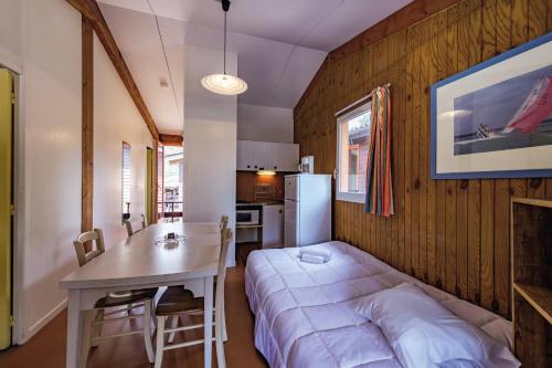 カルカンにあるBelambra Clubs Résidence Carcans - Les Sentesのベッド、テーブル、キッチンが備わる客室です。
