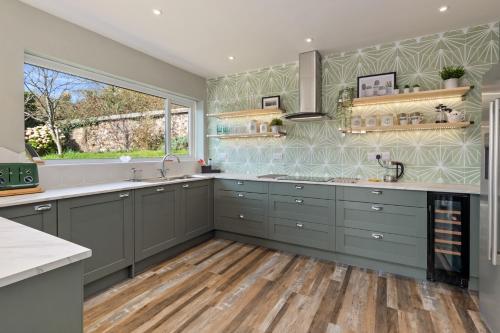 a kitchen with gray cabinets and a large window at Solace - Beautiful Cottage, Views over the Wooded Valley in Stepaside