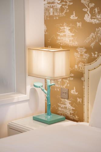 a lamp on a table in a bedroom with a wall with drawings at Dorsett Shepherds Bush London in London