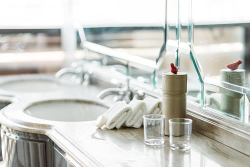 a bathroom counter with two sinks and two glasses at Dorsett Shepherds Bush London in London