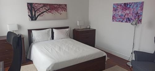 a bedroom with a white bed and a chair at Alojamento Pestana in Horta