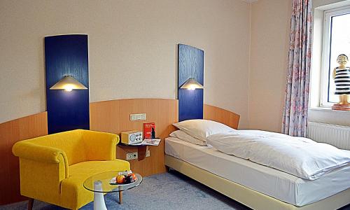 a bedroom with a bed and a yellow chair at Retro - Art - Hotel Lünen in Lünen