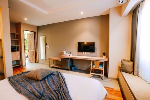 a bedroom with a bed and a desk with a television at Tanaga CoLiving in Seminyak