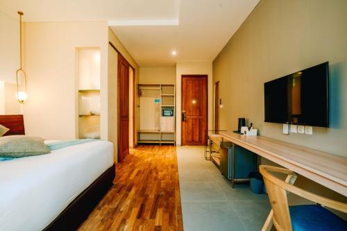 a bedroom with a bed and a desk with a television at Tanaga CoLiving in Seminyak