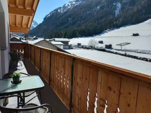 einen Balkon mit einem Tisch und einem schneebedeckten Berg in der Unterkunft Apart Bergglück in Sankt Leonhard im Pitztal