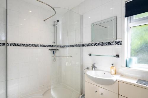 a white bathroom with a shower and a sink at Highlands in Port Isaac