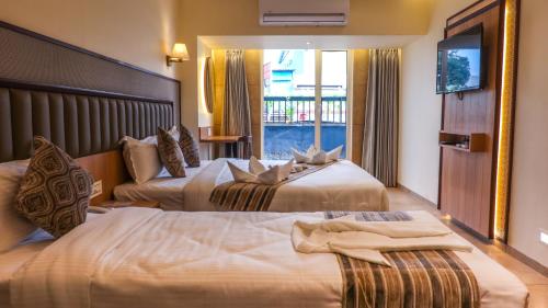 a hotel room with two beds and a window at Rudra Shelter Business Hotel in Vasai