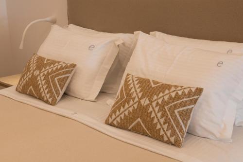 two white pillows and two brown and white pillows on a bed at Elena Hotel Mykonos in Mýkonos City