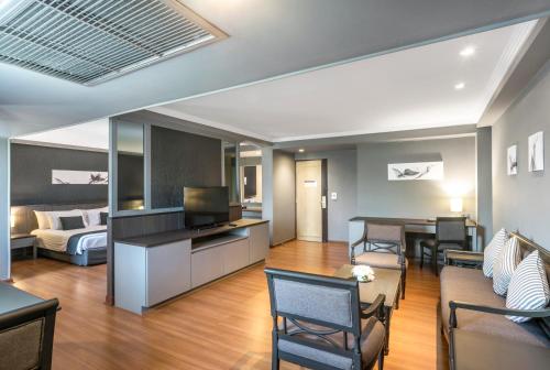 a living room with a couch and a bed and a television at SC Park Hotel in Bangkok