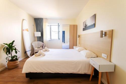 a bedroom with a large bed and a chair at Surfivor Surf Camp in Esmoriz