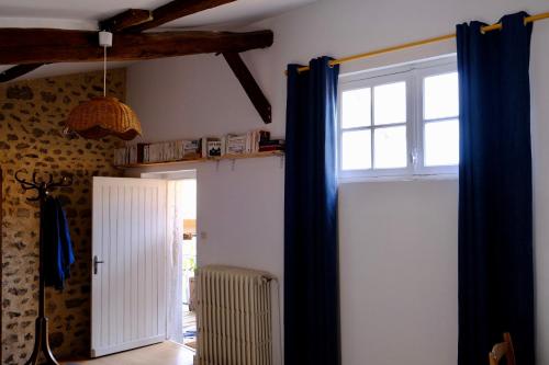Zimmer mit einer Tür und einem Fenster mit blauen Vorhängen in der Unterkunft Le Clou in Chauvigny