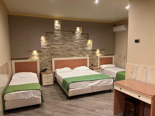 a bedroom with two beds and a stone wall at Hotel Iris in Naples