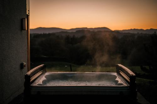 a hot tub in front of a window with the sunset at Cleabarrow View in Windermere