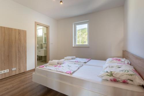 a white bedroom with a bed with two pillows at Sea View Luxury Apartment in Cres
