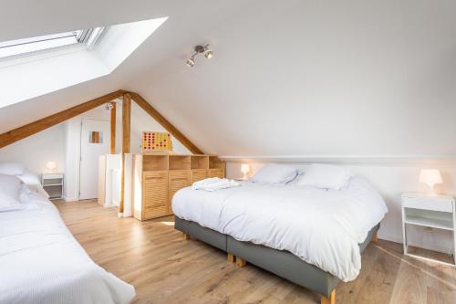 two beds in a attic bedroom with white walls at La Rigaudrye in Ellezelles