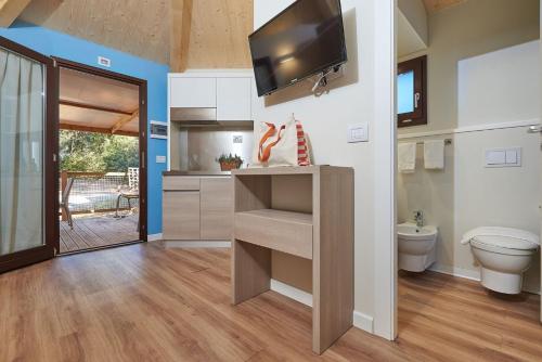 a bathroom with a toilet and a tv on a wall at Paradù EcoVillage & Resort in Marina di Castagneto Carducci