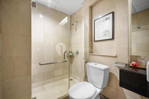 een badkamer met toilet en glazen douche bij Central by Kozystay - Mega Kuningan in Jakarta