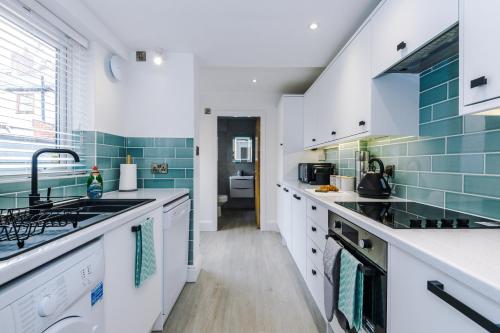 a kitchen with white counters and blue tiles at Phillip House in Chester