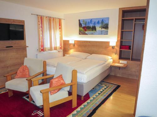 ein Schlafzimmer mit einem Bett, 2 Stühlen und einem TV in der Unterkunft Apartment Hof am Schönbach - STA163 by Interhome in Sankt Jakob