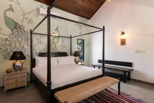 a bedroom with a four poster bed and a table at Jetwing Mahesa Bhawan in Jaffna