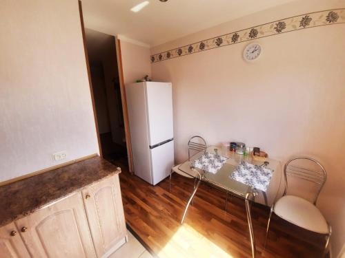 Sunny Apartment في ريغا: مطبخ مع طاولة وثلاجة بيضاء