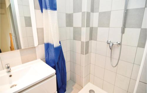 a shower with a blue shower curtain next to a sink at Le Jardin in Le Sambuc