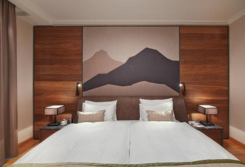 a bedroom with a large bed with mountains on the wall at Grand Hotel des Bains Kempinski in St. Moritz