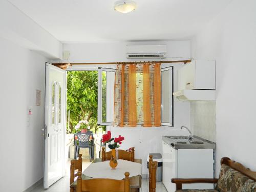 eine Küche und ein Esszimmer mit einem Tisch und einem Fenster in der Unterkunft ARISTON APARTMENTS in Póros