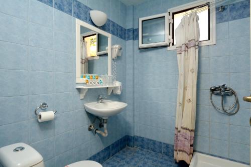 a blue bathroom with a sink and a toilet at Katia Hotel in Afissos
