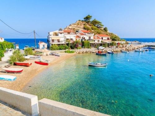 a beach with boats in the water next to houses at HOKKUM STUDIOS in Kokkari