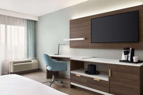 a hotel room with a desk and a tv on a wall at Wyndham Garden Totowa in Totowa