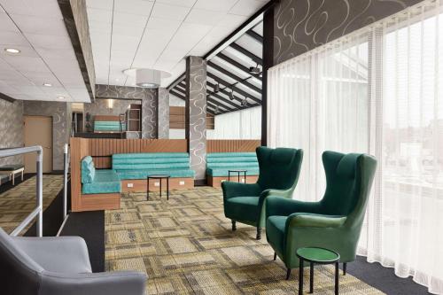 a waiting room with green chairs and a table at Wyndham Garden Totowa in Totowa