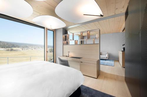 a bedroom with a large white bed and a large window at Hôtel des Horlogers in Le Brassus