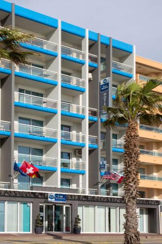 an apartment building with a palm tree in front of it at Best Western Plus Hotel Canet-Plage in Canet-en-Roussillon