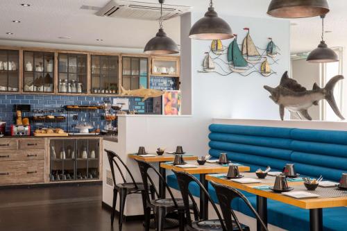 a restaurant with wooden tables and blue chairs at Best Western Plus Hotel Canet-Plage in Canet-en-Roussillon