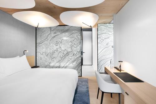 a bedroom with a bed and a desk and a wall at Hôtel des Horlogers in Le Brassus