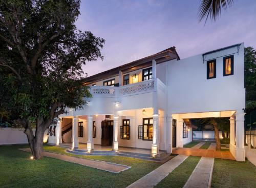 an exterior view of a white house with a tree at Jetwing Mahesa Bhawan in Jaffna