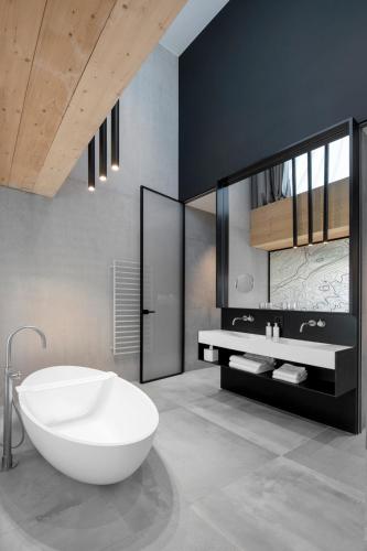a bathroom with a white tub and a sink at Hôtel des Horlogers in Le Brassus