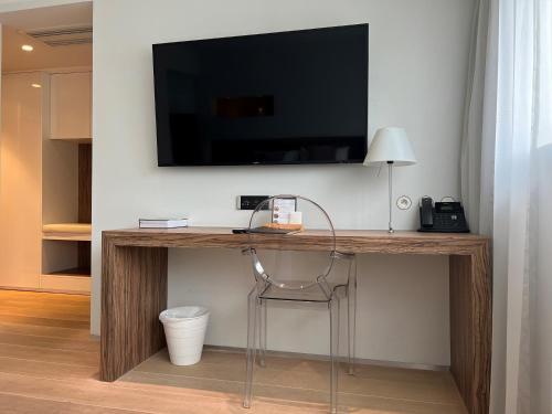 a desk with a television on a wall with a chair at HasHotel in Hasselt