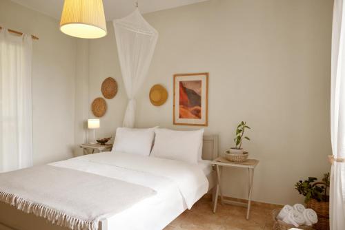 a white bedroom with a bed and two tables at Kopana Resort in Pefkochori
