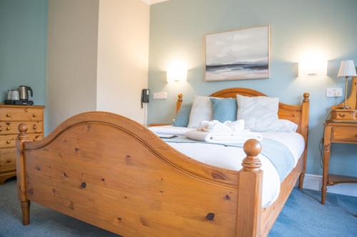 a bedroom with a wooden bed with white sheets at Tyn-y-Coed Inn in Betws-y-coed