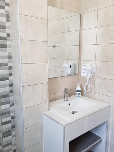 a bathroom with a white sink and a mirror at Virvilis Apartments in Sivota