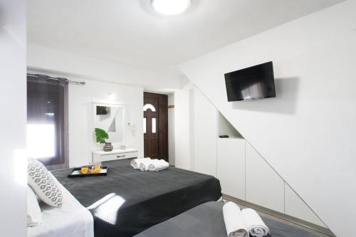 a white room with a bed and a tv at Bohemian Townhouse in Skiathos Town