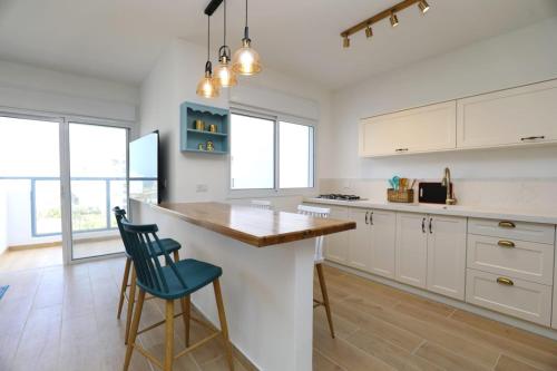 a kitchen with white cabinets and a counter with a blue chair at דירה בטורקיז in H̱adera