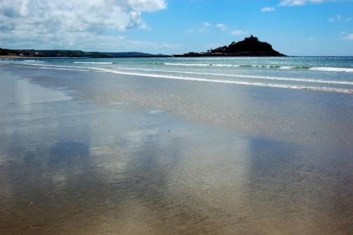 a sandy beach with waves on the ocean at The Mexico Inn, Flat One in Ludgvan
