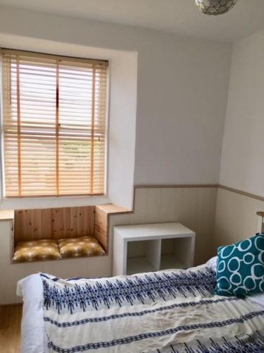 a bedroom with a bed and a window with a table at The Mexico Inn, Flat One in Ludgvan