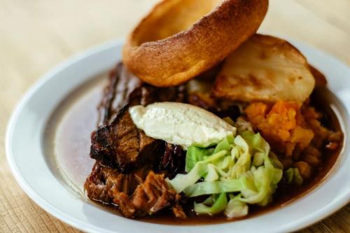 a plate of food with meat and vegetables and a bagel at The Mexico Inn, Flat One in Ludgvan