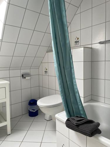 Un baño con inodoro y una cortina de ducha verde. en Ferienwohnung LaMer, en Borkum